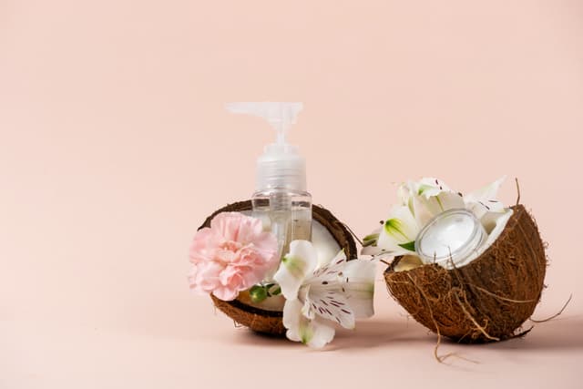 Coconut oil inside coconut on pink background